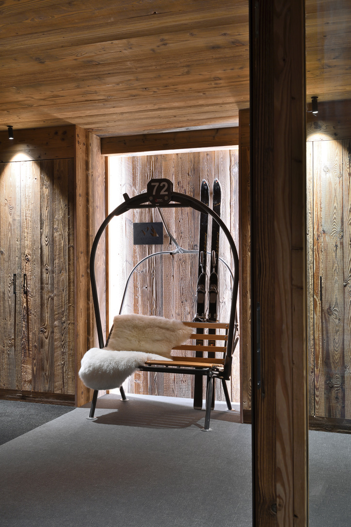 Fauteuil ancien télésiège reconverti dans l'entrée du chalet, peau de mouton et skis vintage