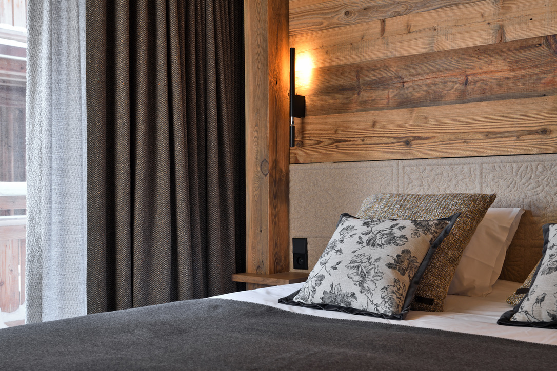 Détail d'une chambre du 1er étage : oreillers à motif floral, applique chaude et rideaux en laine