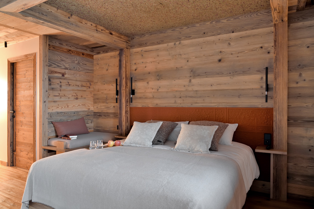 Chambre du 1er étage avec tête de lit terracotta, banquette de lecture et boiseries claires