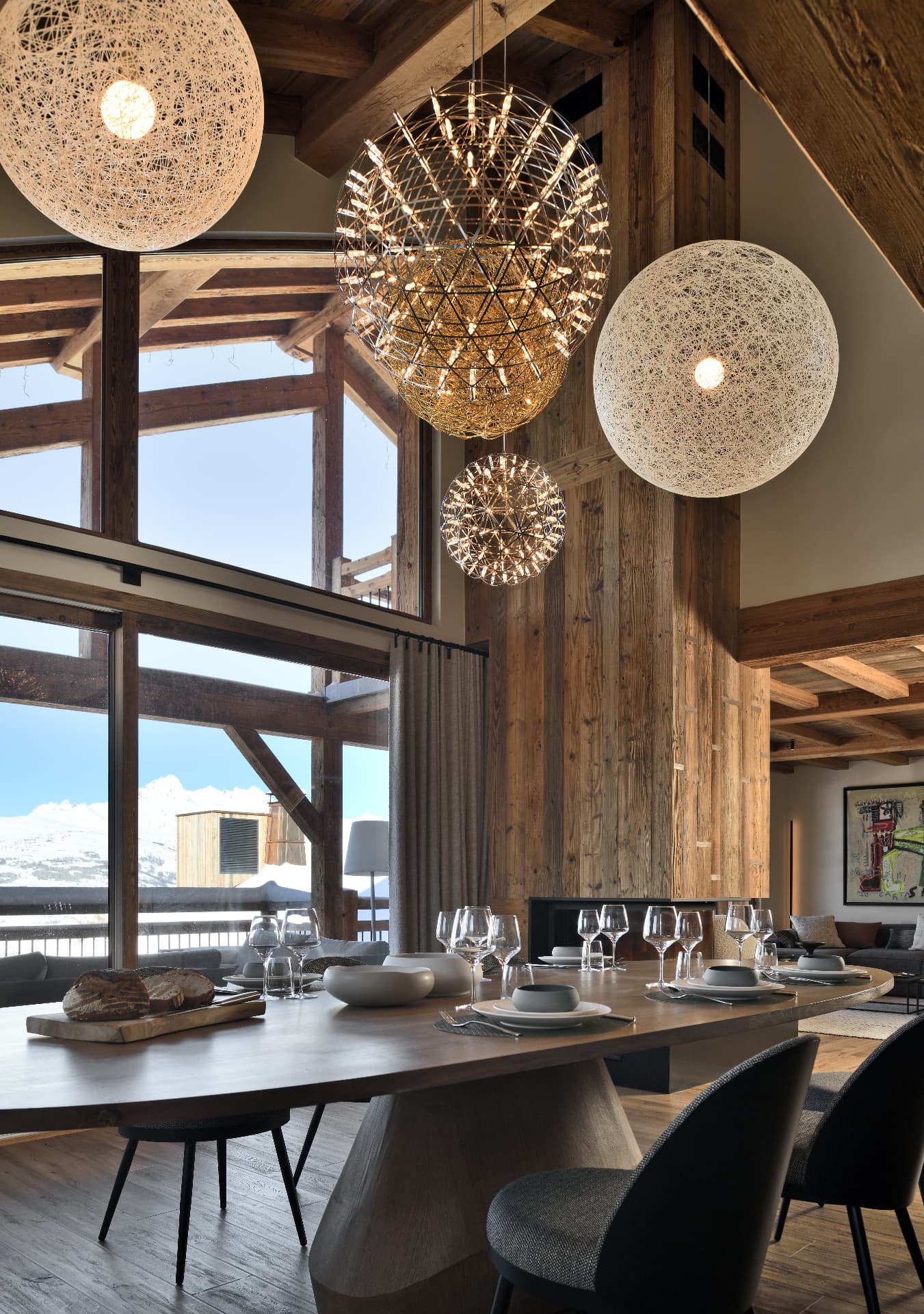Grande table dressée face aux sommets, sous les suspensions dorées du séjour d'Epicime Lodge