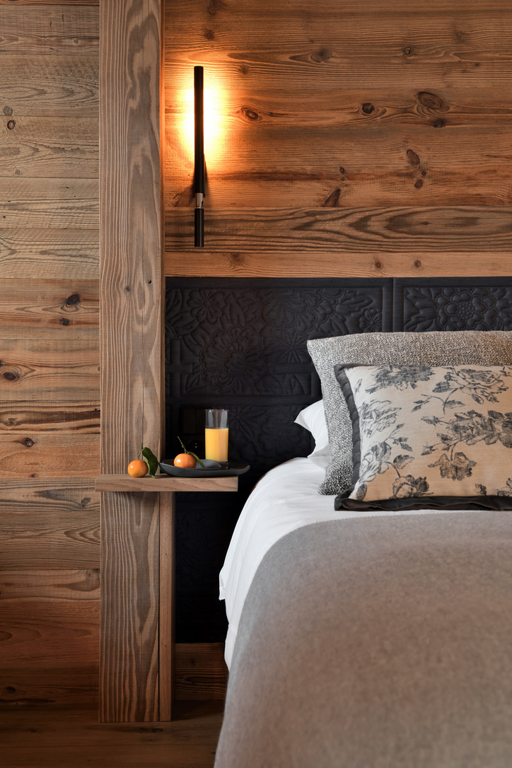 Table de chevet d'une chambre du 1er étage avec jus d'orange, tête de lit sculptée noire